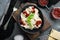 Appetizing ravioli with tomato sauce  cheese and basil with basil parmesan and tomatoe in black bowl   on gray background   top