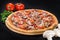 Appetizing Salami pizza with salami, mozzarella, pepper and olives on wooden board on dark background