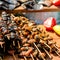 Appetizing skewers of mussels, strung on wooden sticks. Delicious seafood on a wooden background.