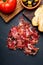 Appetizing slices Iberian ham in the foreground. Olive oil, bread, fresh tomato, olives. Black background. Rustic and homemade