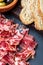 Appetizing slices Iberian ham in the foreground. Olive oil, bread, fresh tomato, olives. Black background. Rustic and homemade