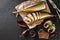 Appetizing smoked fish with spices, cutlery, pepper and bread on craft paper over dark stone background. Sandwich with smoked