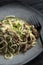 Appetizing spaghetti with meat and herbs on a plate on a table in a restaurant. Close-up. Vertical