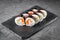 Appetizing sushi roll futomaki with cucumber crab stick and masago on a black stone plate