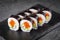 Appetizing sushi roll futomaki with cucumber and salmon on a black stone plate