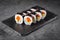 Appetizing sushi roll futomaki with cucumber and salmon on a black stone plate