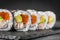 Appetizing sushi roll futomaki salmon, shrimp and avocado on a black stone plate