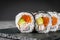 Appetizing sushi roll futomaki salmon, shrimp and avocado on a black stone plate