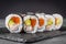 Appetizing sushi roll futomaki salmon, shrimp and avocado on a black stone plate