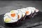 Appetizing sushi roll futomaki yin yang with salmon and avocado on a black stone plate