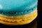 Appetizing two-color macarons blue and yellow colors on a black background. Close-up