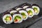 Appetizing vegan sushi roll futomaki with pepper cucumber and avocado salad on a black stone plate