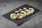 Appetizing vegan sushi roll futomaki with pepper cucumber and avocado salad on a black stone plate