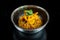 Appetizing wok rice with shrimp, vegetables and sesame seeds in a black bowl on a black background with reflection. Asian street