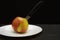 Apple on a black background with a knife inside on a white plate