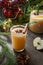 Apple cider cocktail with cardamon and star anise on black table with fir tree branches.