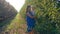 Apple crop, young mother with little girl on hands harvest in autumn orchard between rows of trees in light