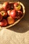 Apple harvest in a basket with a lot of red ripe fruits on bedcover background.