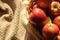 Apple harvest in a basket with a lot of red ripe fruits on draperied bedcover.