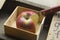 Apple and knife in a wooden box for produce sampling.