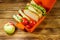 Apple and lunch box with sandwiches and fresh vegetables on wooden table