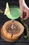 Apple Martini cocktail with garnish on wooden board and woman hand with rosemary