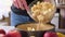 Apple pie preparation series - woman pours chopped apples into a baking dish