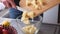 Apple pie preparation series - woman pours chopped apples into a glass bowl