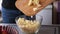 Apple pie preparation series - woman pours chopped apples into a glass bowl