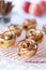 Apple rose pastries on a cooling rack with apples and cinnamon sticks in soft focus in behind.