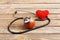 Apple, stethoscope and heart on wooden background