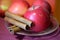 Apples and cinnamon sticks on the saucer on purple surface