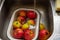 Apples in an enamel bowl under the flow water from tap in the sink