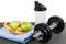 Apples, measures tape on blue towel, plastic shaker and dumbbell