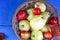 Apples and plums in a basket on wooden background