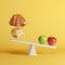 Apples tipping seesaw with floating burger and pork leg on opposite end on yellow background