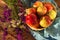 Apples in a woven vase with meadow flowers on a wooden table