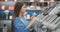 In the appliances store, a brunette woman in a shirt chooses a blender for shopping by viewing and holding the device in