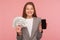 Apply online, loan application. Portrait of happy smiling businesswoman in suit jacket holding dollar banknotes and cellphone