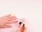 Applying nude nail polish to woman`s hand