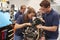 Apprentice car mechanics working on an engine