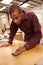 Apprentice Finishing Wood In Carpentry Workshop