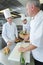 Apprentices cooks watching chef garnishing dish