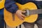 Approach to the hand of an elderly man sitting holding a guitar dressed in a blue shirt with a