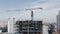 An approaching aerial shot from the side of a gray high-rise office building under construction. Lifting from a bird`s