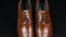 Approaching, pair of brown classic men`s shoes standing on on a black background. Men`s fashion