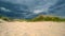 The approaching storm cloud on the beach with dunes and pure white sand