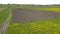 Approaching tractor cultivating arable land for seeding crops, Yellow rapeseed .Aerial view