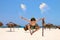 Appy young man jumps for joy on the beach, against blue sky and ocean