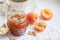 Apricot jam in a glass bowl, fresh apricots in a basket on a white background